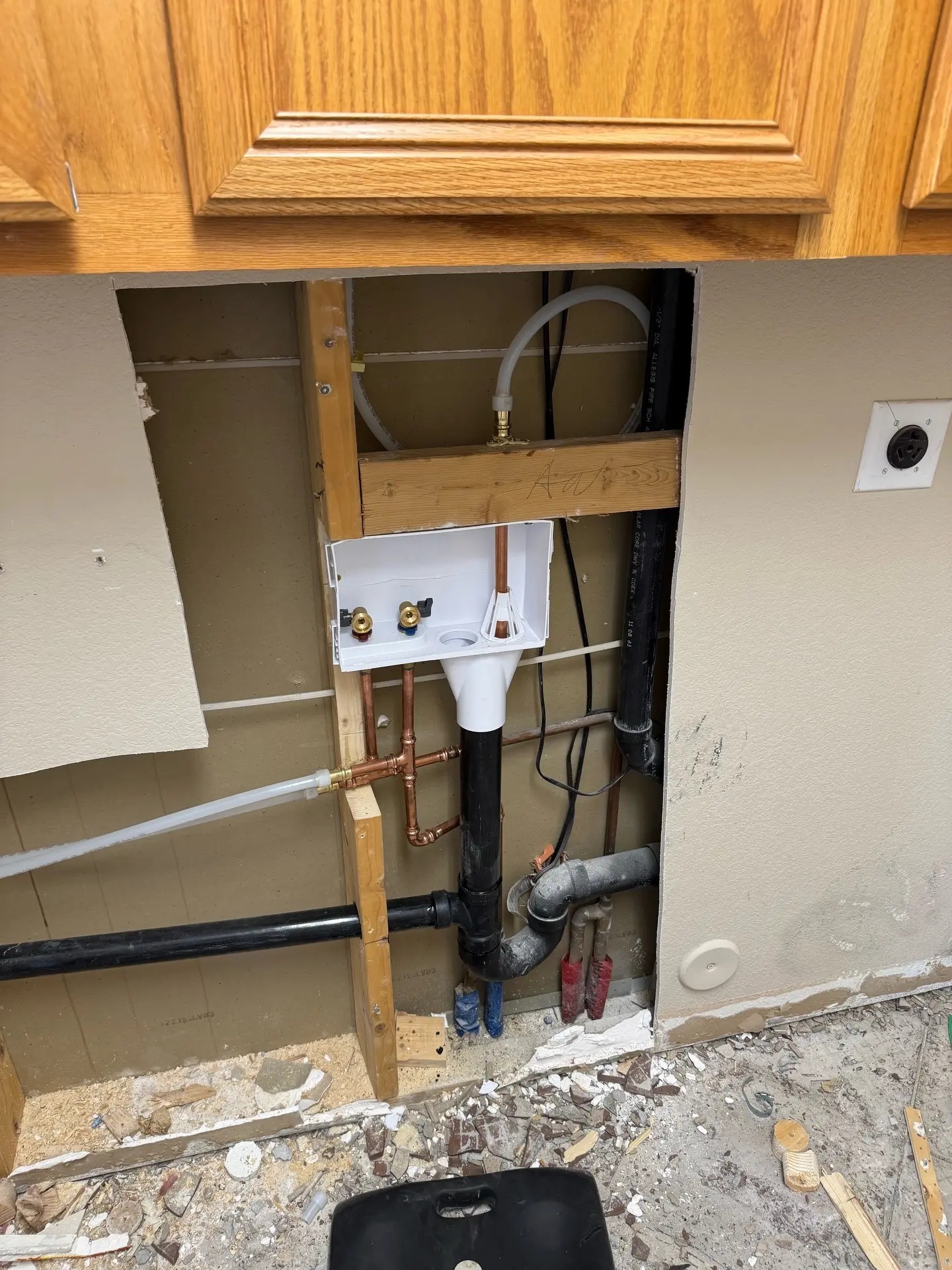 Close view of a laundry outlet box with shutoff valves and copper piping installed in an open wall.